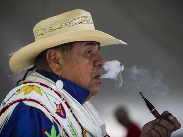 Emerson Nanigishkung, an Ojibway from the Rama Mnjikaning First Nation in Ontario, enjoys a pipe after dancing  at the 30th edition of the Echoes of a Proud Nation Pow-Wow in Kahnawake on Sunday, July 10, 2022.