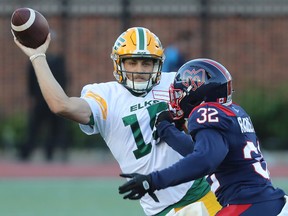 Edmonton Elks quarterback Taylor Cornelius (15) throws the ball as the Montreal Alouettes' Rodney Randle Jr. (32) gets too close for comfort during first half CFL action in Montreal on Thursday July 14, 2022.