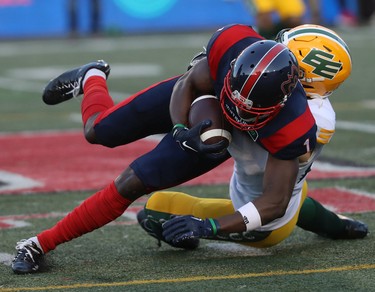 Montreal Alouettes's Hergy Mayala (1) is brought down by Edmonton Elks's Scott Hutter (20) during first-half CFL action in Montreal on Thursday, July 14, 2022.