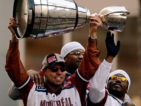 The Montreal Alouettes' Stéphane Fortin, from left, Kevin Johnson and Thomas Haskins celebrate with Grey Cup during parade along Ste-Catherine St., on Nov. 27, 2002.