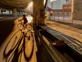 A woman cycles past the Canada Malting plant and under the Bonaventure Expressway July 17, 2022.