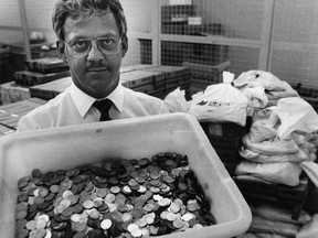 René Arbour of Banque Nationale displays a bin full of old Champlain bridge tokens as he stands in front of bags containing about 300,000 others.