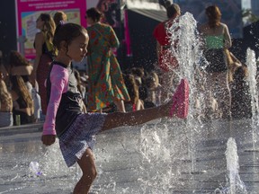 A youngster plays at the water fountain on Day 1 of the Osheaga festival at Parc Jean-Drapeau in Montreal Friday, July 29, 2022.