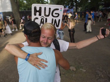 Jean-Philippe Marier hugs a man, and records the hug with a device in his left hand, at the Osheaga Festival at Jean-Drapeau Park in Montreal Sunday, July 31, 2022. Marier is the founder of HUG4LOVE and has a goal to improve everyone's mental wellness.