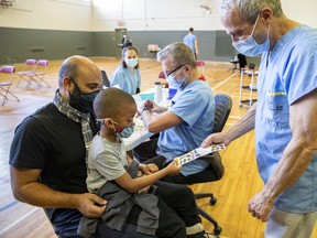 Retired doctor Peter Forbes offers Benjamin Gueyaud, sitting on father Olivier's lap, a sticker after receiving the COVID-19 vaccine at a clinic for children age five to 11 in Verdun in November 2021. Canada’s drug regulator announced Thursday that it has approved Moderna’s COVID-19 vaccine for infants and preschoolers.