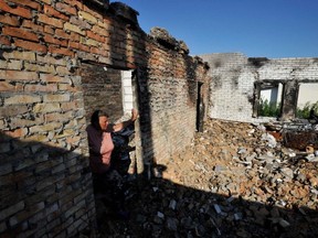 Olga, 67, looks at her house destroyed as a result of shelling in the village of Moshchun, Kyiv region, Ukraine, July 28, 2022.