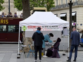 A tourist bus drives past a curbside COVID-19 testing tent placed along the Avenue des Champs-Elysees in Paris on July 1, 2022. - The World Health Organization said on June 30, 2022, it expected "high levels" of COVID-19 in Europe this summer and called on countries to monitor the spread as cases tripled in the past month.