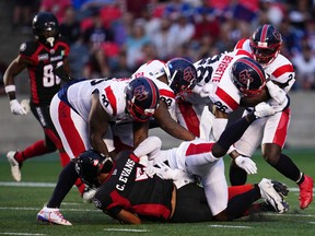 Five Alouettes players gang-tackle Redblacks quarterback Caleb Evans during first half in Ottawa Thursday night.