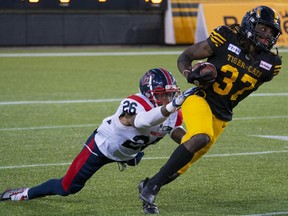 Tiger-Cats' Lawrence Woods breaks a tackle by Alouettes linebacker Tyrice Beverette during first-half action in Hamilton Thursday night.