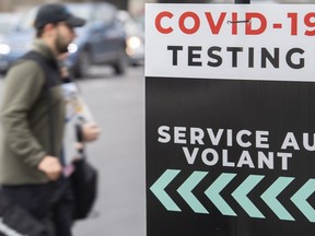 A man walks by a sign for a COVID-19 testing centre in Montreal, Sunday, Oct. 10, 2021.