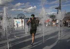 A man runs through a water fountain on Day 1 of the Osheaga festival at Parc Jean-Drapeau in Montreal Friday, July 29, 2022.