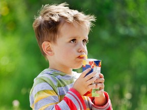 Young boy sips from a juice box on a sunny summer afternoon.