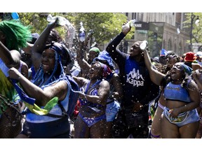 People dance in the street as they take part in the Carifiesta Parade in Montreal, on Saturday, July 2, 2022.