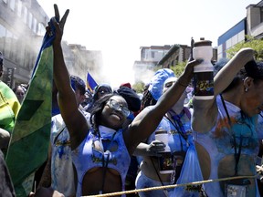 People dance in the street as they take part in the Carifiesta Parade in Montreal, on Saturday, July 2, 2022.