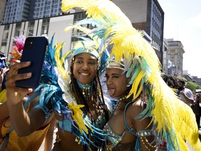 Performers stop to take a selfie as they take part in the Carifiesta Parade in Montreal, on Saturday, July 2, 2022.