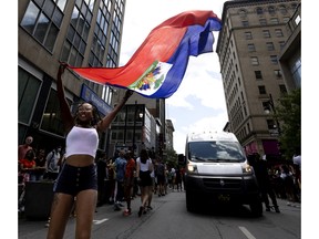 A woman waves the Haitian flag as she dances during the Carifiesta Parade in Montreal, Saturday, July 2, 2022.