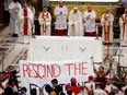 Indigenous people hold a protest banner as Pope Francis celebrates mass at the National Shrine of Sainte-Anne-de-Beaupré on July 28, 2022.