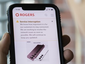 A person looks at their cell phone displaying a Rogers service interruption alert in Montreal, Friday, July 8, 2022.