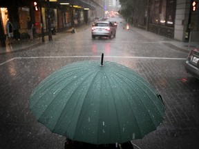 Lone person is sheltered from rain at Ste-Catherine St. and Aylmer St., during rainstorm in Montreal.