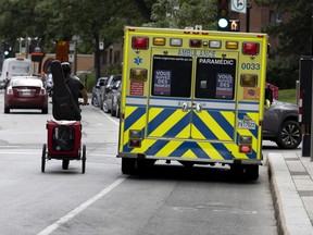 A cyclist films himself as he makes his way around a stopped ambulance at the CHUM hospital in Montreal on Thursday, July 21, 2022.