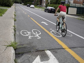 A cyclist rides past a blood stain that marks the spot where a young man was shot by Abdullah Shaikh while he was on a Laval bike path. Shaikh, a suspect in 3 murders, who was later shot by police during a raid on his motel room, in Montreal on Thursday, August 4, 2022.