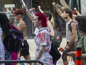 People silently raise their arms while walking on St-Laurent Blvd. in Montreal Sunday, August 7, 2022. This was during a protest march that was made after the Pride Parade was cancelled.