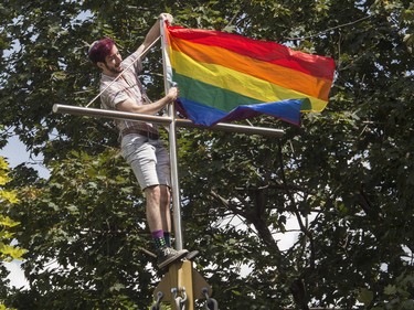A man hangs a flag in a Plateau Mont-Royal park in Montreal Sunday, August 7, 2022. This was during a protest march that was made after the Pride Parade was cancelled.