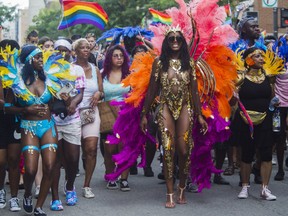 People walk behind a truck operated by Afro Pride as it was playing music in Montreal Sunday, Aug. 7, 2022, after the annual Pride Parade was cancelled.