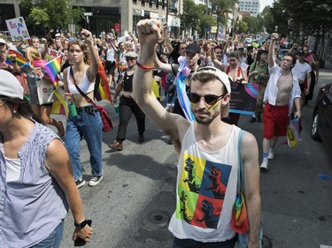 People silently raise their arms while walking on St-Laurent Blvd. in Montreal Sunday, Aug. 7, 2022. This was during a protest march that was made after the Pride Parade was cancelled.