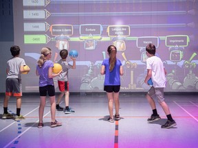 Kids play STORÏA, via Lü Systems, an interactive application that allows teachers to create timelines to be put back in order through ball throws.