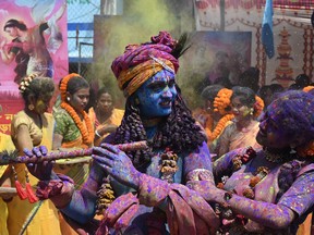 Youths smeared in coloured powder and dressed as Lord Krishna (left) and deity Radha celebrate Holi in Kolkata March 17, 2022.