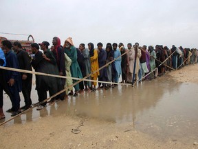 Flood-affected people stand in a queue as they wait to receive food packets being distributed by Pakistan's army after they were forced to leave their homes following heavy monsoon rainfall on the outskirts of Hyderabad in Sindh province on August 24, 2022. - Record monsoon rains were causing a "catastrophe of epic scale," Pakistan's Climate Change Minister said on August 24, announcing an international appeal for help in dealing with floods that have killed more than 800 people since June.