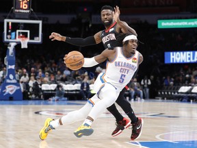Luguentz Dort of the Oklahoma City Thunder drives to the basket around Houston Rockets forward David Nwaba in November 2021.
