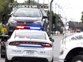 Montreal police work Friday, August 12, 2022 at the scene of an overnight shooting that left a 25-year-old woman injured in the east end. Three cars were seized in the investigation.