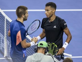 Borna Coric, left, of Croatia shakes hands with Montreal's Félix Auger-Aliassime after their match at the Western & Southern Open tennis tournament Friday, Aug. 19, 2022 in Mason, Ohio.