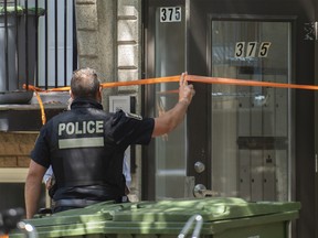 A police officer is shown at an apartment building near Ash Ave. and Le Ber St. in Pointe-St-Charles on Sunday, August 7, 2022, where a person died after falling down a staircase during an altercation with another person.