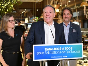 Coalition Avenir Québec Leader François Legault speaks to reporters during a campaign stop in a market, Monday, August 29, 2022 in Levis, Que. Legault is flanked by local candidates Stephanie Lachance, left, and Mathieu Rivest. Quebecers are going to the polls for a general election on Oct. 3.