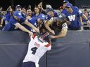 Winnipeg Blue Bombers fans push Montreal Alouettes quarterback Dominique Davis off the wall as he tries to celebrate his touchdown in Winnipeg on Aug. 11, 2022.