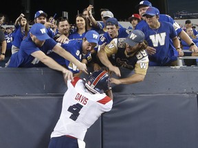 Winnipeg Blue Bombers fans push Montreal Alouettes quarterback Dominique Davis as he tries to celebrate his touchdown in Winnipeg on August 11, 2022.