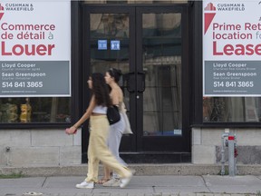 People walk past bilingual signs for a commercial space for rent in Westmount last week.