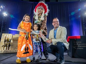 Denis Gros-Louis, right, director general of the First Nations Education Council, presents a wampum and talking stick to Régis Penosway, chief of the Kitcisakik First Nation, and his daughters Deanna, left, and Aimé during ceremony marking an agreement between the federal government and 22 First Nations advancing their control over education, in Kahnawake on July 14, 2022.