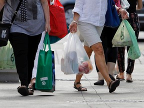A shopper uses plastic bags to carry her groceries as another carries a reusable bag near Atwater Market in Montreal on August 23, 2016. A bylaw barring the distribution of plastic shopping bags in the city's 19 boroughs goes into effect on Tuesday, Sept. 27, 2022.