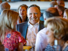 Quebec Premier Francois Legault smiles while sitting for lunch with local Coalition Avenir Québec candidates at a  campaign stop in Vaudreuil—Dorion on Friday, Sept. 2, 2022.