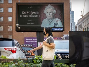 A pedestrian walks past a billboard at the corner of de Maisonneuve Blvd. and de la Montagne St. paying tribute to Queen Elizabeth in Montreal Friday Sept. 9, 2022.