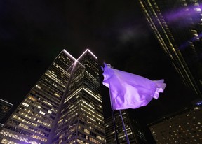 A pole dancer dressed in a long, flowing white gown performs as the ring is lit up during an event to mark the 60th anniversary of Place Ville Marie, in Montreal on Wednesday, Sept. 14, 2022.