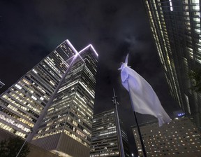 A pole dancer dressed in a long, flowing white gown performs as the ring is lit up during an event to mark the 60th anniversary of Place Ville Marie, in Montreal, on Wednesday, Sept. 14, 2022.