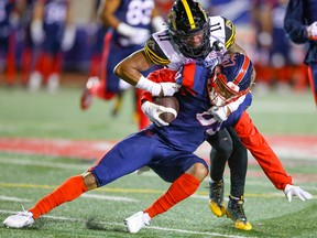 Alouettes receiver Tyson Philpot is tackled by Hamilton Tiger-Cats Kameron Kelly after catching a pass in Montreal on Friday, Sept.  23, 2022.