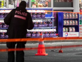 A Montreal police officer stands near a gun at the service station where a shootout occurred in St-Léonard on Thursday December 20, 2018. Sébastien Beauchamp, a man who had close ties to the Hells Angels, was killed.