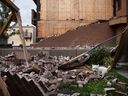 A dog walks amidst a collapsed brick facade of an apartment building that spilled into a residential backyard in Halifax after Tropical Storm Fiona on Saturday, September 24, 2022.