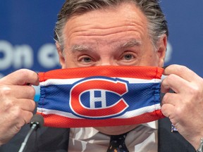 François Legault puts on a Montreal Canadiens face mask as he finishes a COVID-19 press briefing in May 2020 in Montreal.
